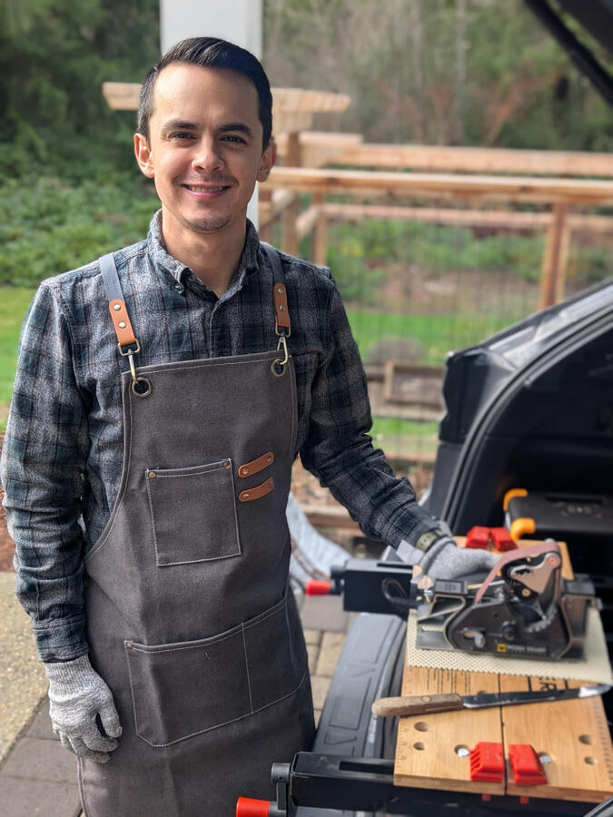 Man standing at work table with sharpening tool Man standing at work table with sharpening tool
